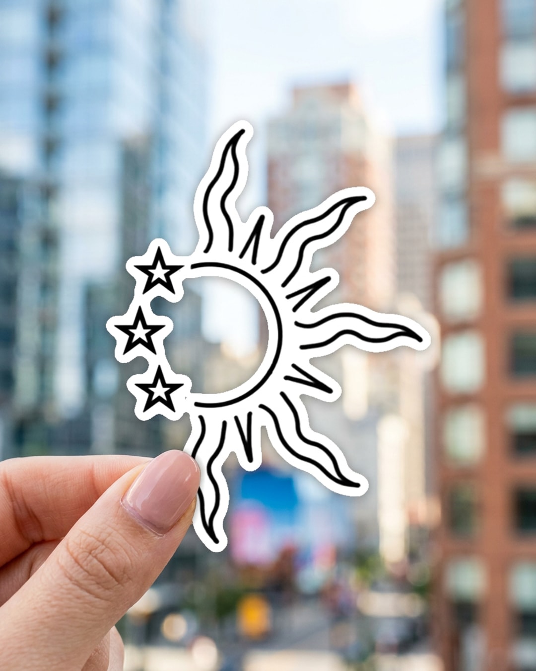 Pegatina Sol de Mayo argentino con tres estrellas sostenida en la mano, a tamaño real