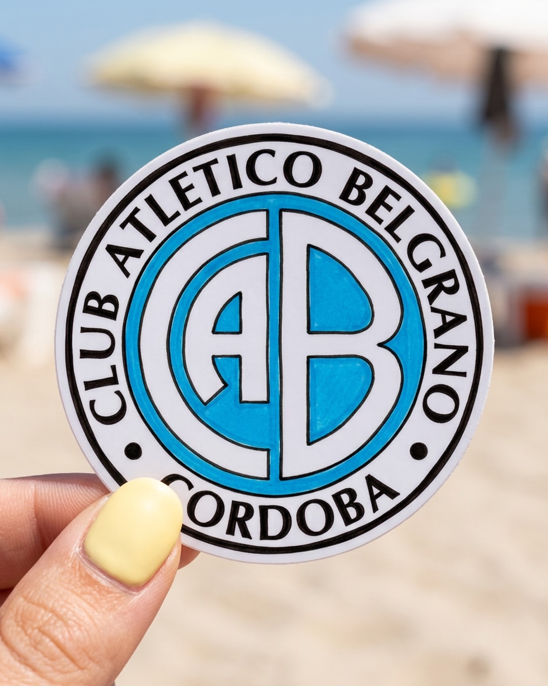Pegatina Escudo de Belgrano de Córdoba sostenida en la mano, a tamaño real