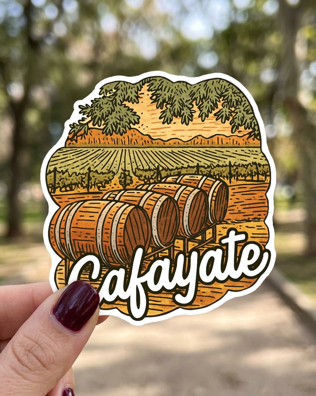 Pegatina Cafayate con viñedos y barricas de vino sostenida en la mano, a tamaño real