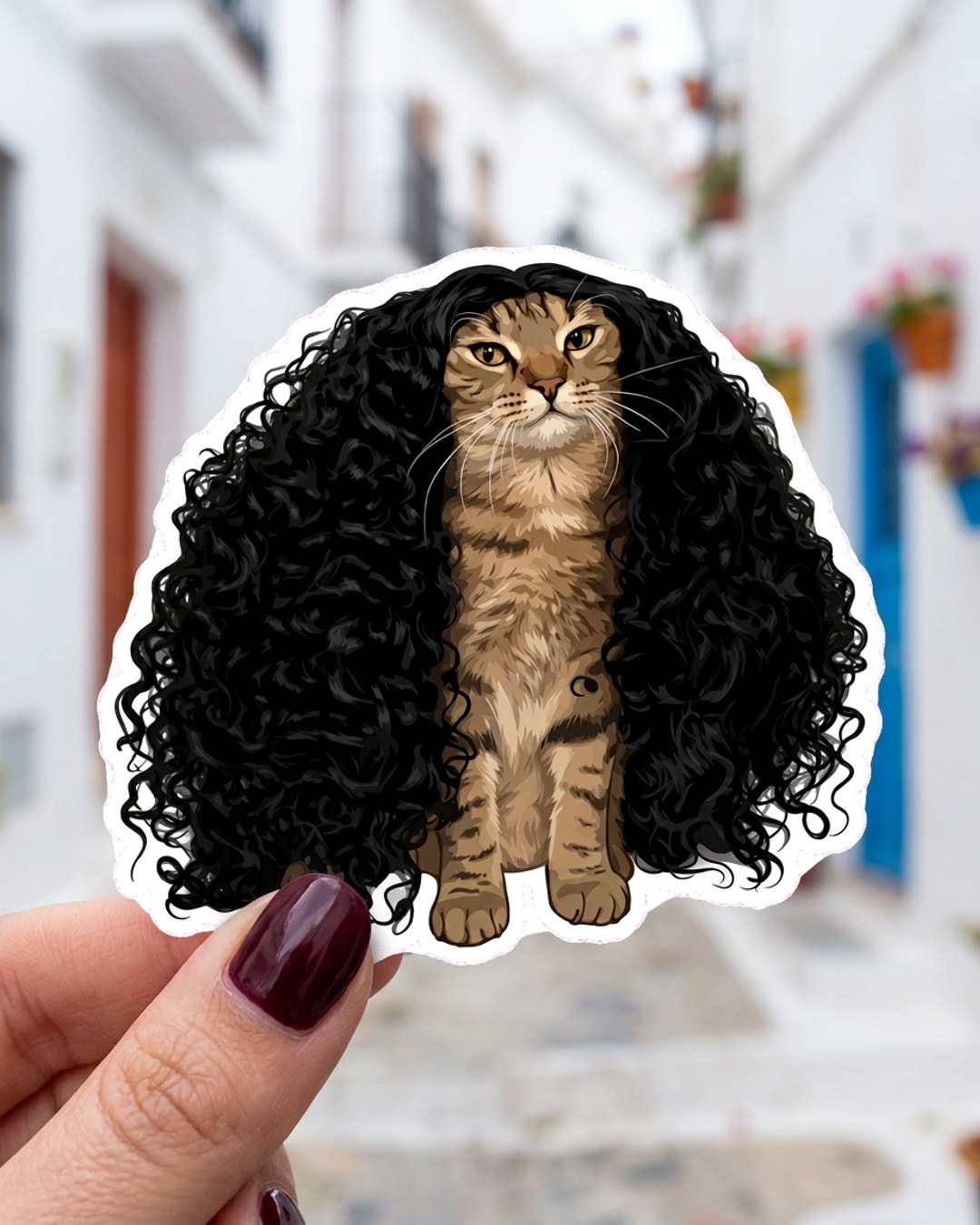 Pegatina Gato Atigrado con Peluca Rizada Negra sostenida en la mano, a tamaño real