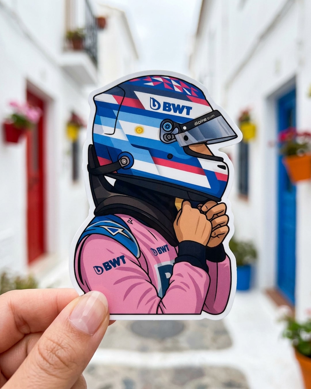 Pegatina Piloto F1 Argentino con Casco y Mono Rosa BWT sostenida en la mano, a tamaño real