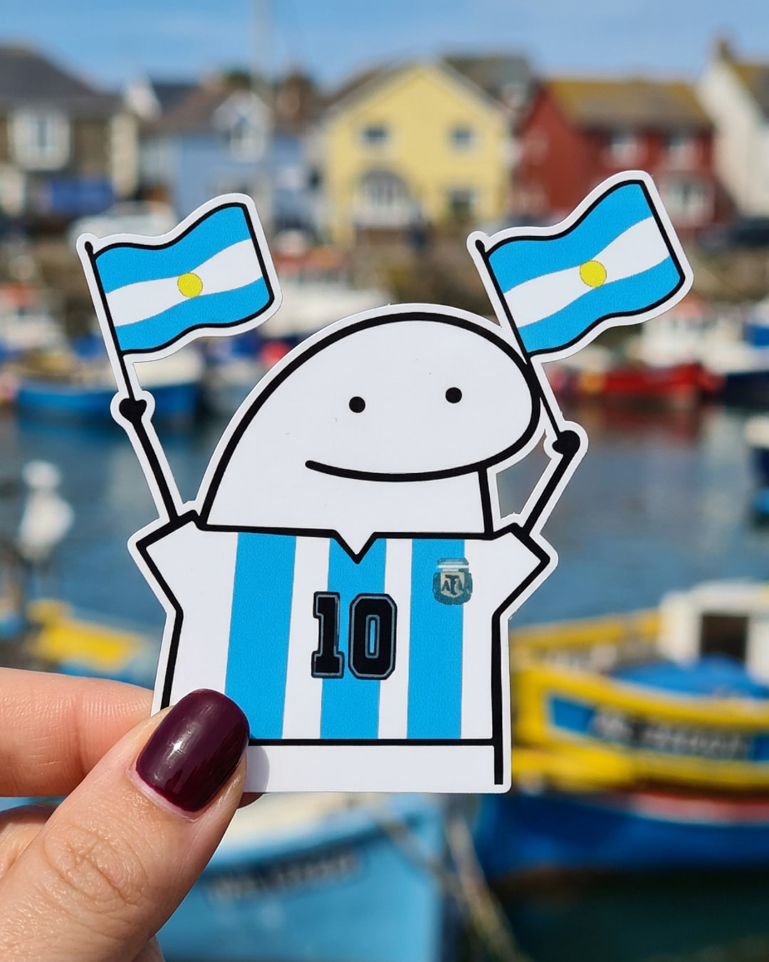 Pegatina Flork con camiseta de Argentina 10 y banderas sostenida en la mano, a tamaño real