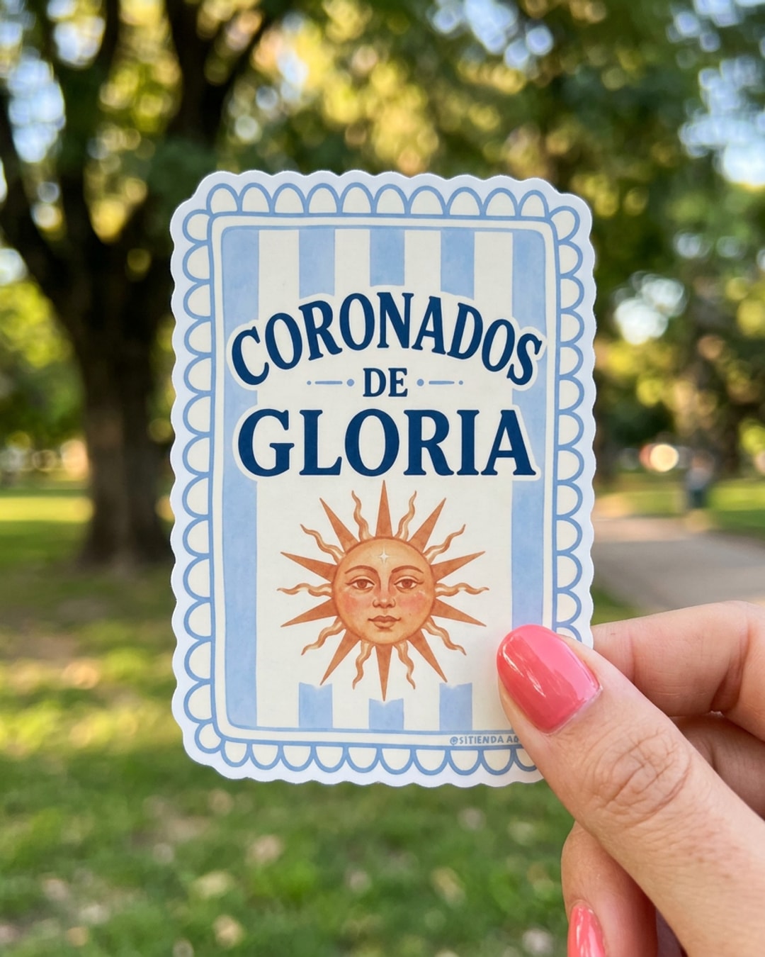 Pegatina Coronados de Gloria con Sol de Mayo sostenida en la mano, a tamaño real