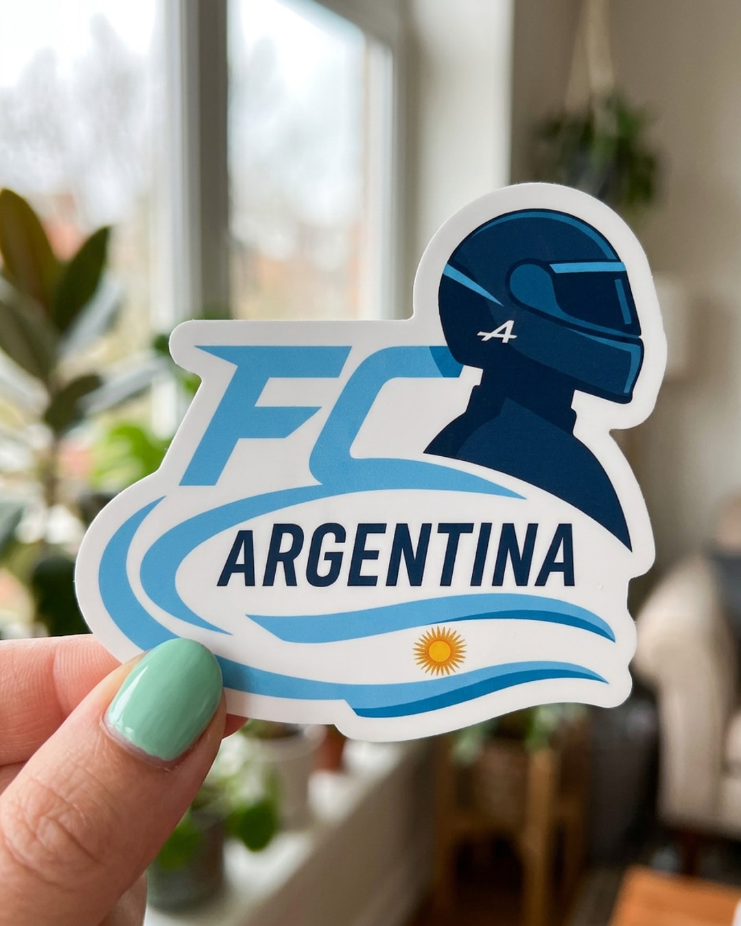 Pegatina FC Argentina con casco de piloto F1 sostenida en la mano, a tamaño real